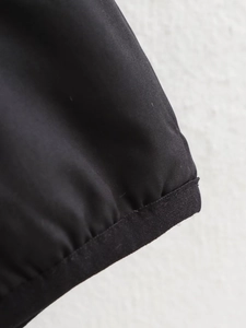Detailed close-up of the black ribbed hem and woven texture on a reversible jacket
