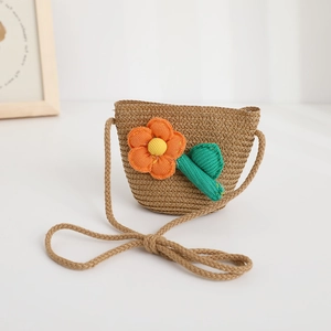 Detail of woven straw bag for kids featuring decorative floral accents and cotton rope strap