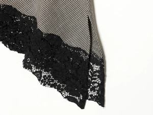 Detail of asymmetrical houndstooth skirt hem with black floral lace trim and textured fabric