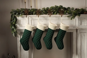 Details von vier dunkelgrünen und cremefarbenen Strick-Weihnachtssocken am Kamin