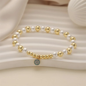 Détail du bracelet en perles avec billes dorées, perles et un pendentif pavé turquoise