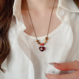 Détail du pendentif cœur avec emblème de planète et perles en bois multicolores