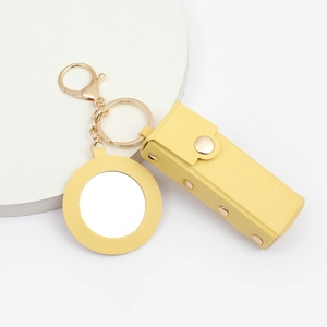 Detail of yellow PU leather lipstick holder with mirror and golden keychain accessory