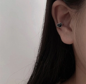 Detail of a minimalist black heart ear cuff clip worn on the earlobe without piercing