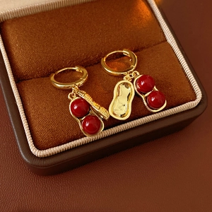 Detail of gold-plated peanut earrings with red glass beads in a brown velvet box