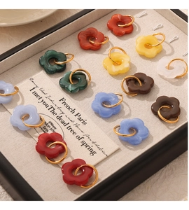 Macro view of multi-colored resin flower earrings in a beige jewelry box