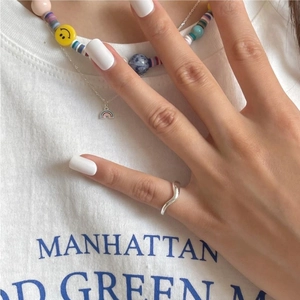 Close-up of a silver wave ring and colorful beaded necklace worn on a model