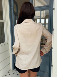 Beige pleated long sleeve shirt for women featuring textured chiffon fabric from a back view