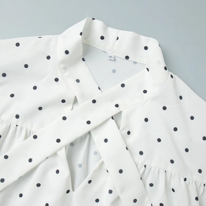 Detail of white polka dot chiffon top with a crossed V-neckline and bell sleeves