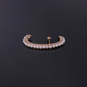 Close-up of rose gold plated ear cuff with white faux pearls on a black surface