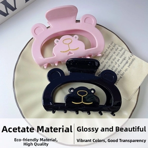 Detail view of pink and black bear-shaped acetate hair claws with gold-outlined faces