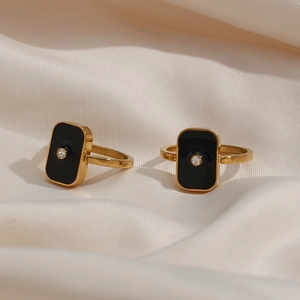 Détails de bagues dorées 18K avec émail noir et cristaux sur tissu de soie