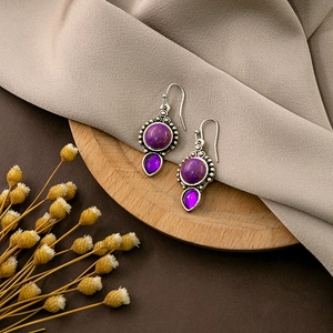 Detailed close-up of retro silver earrings with purple stones on a rustic wooden base