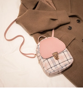 Detail of pink faux leather flap and classic plaid pattern with gold metal lock closure