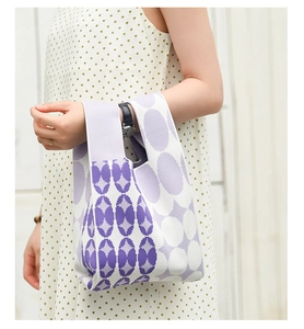 Detail of purple and white geometric knit tote bag held by model with polka dot dress