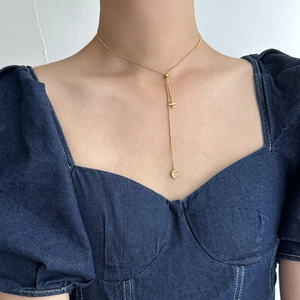 Close-up of gold star and crescent moon pendant on minimalist Y-shaped chain