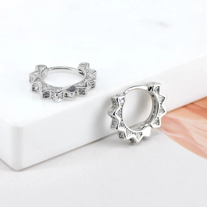 Macro shot of silver gear-shaped hoop earrings with sparkling cubic zirconia inlay