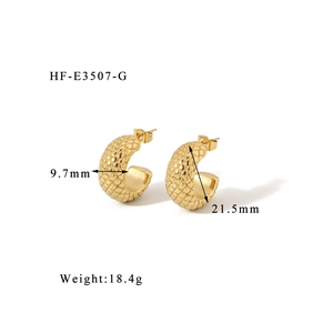 Detail shot of chunky gold C-shape earrings with intricate scale texture and glossy finish