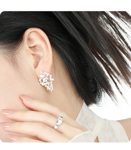 Close-up of matte silver irregular hollow twig earrings on a model's ear lobe