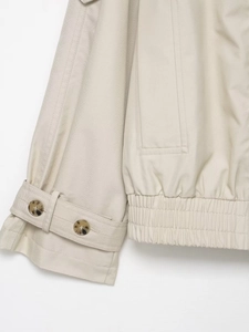 Detail of beige double-breasted jacket cuff strap and elastic drawstring hemline