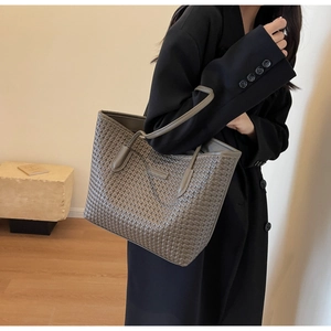 Detail of grey woven tote bag carried by a model in a professional suit outfit
