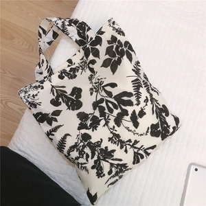 Detail of floral canvas tote bag with black leaf patterns on white cotton fabric texture
