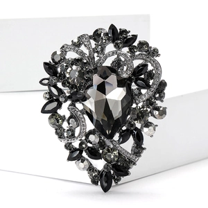 Macro shot of heart-shaped brooch with grey pear-cut crystal and black rhinestones