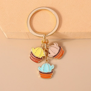 Detailed close-up of golden keychain with colorful enamel cactus pot pendants