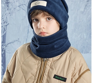 Close-up of kids navy fleece hat and neck warmer set worn outdoors in a winter forest