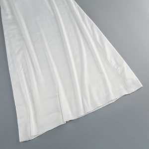 Gros plan détaillé du tissu blanc léger montrant la texture et le drapé de la robe de soirée