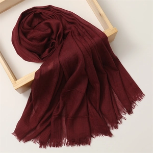 Detail view of burgundy cotton linen scarf with frayed edges on a wooden frame