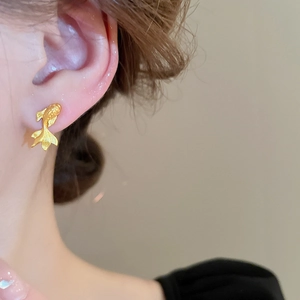 Close-up of golden koi fish stud earring worn by model showing exquisite carved scales