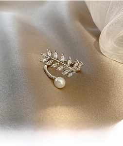 Macro di anello aperto in argento con foglia di zircone e perla su seta champagne
