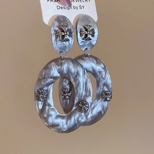 Detail of acrylic oval earrings with gothic cross accents and grey marble texture