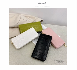 Detail of crocodile pattern long wallets in green, white, black and pink with gold zippers