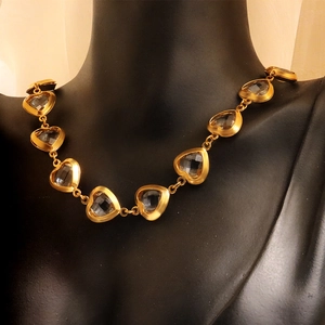 Minimalist golden heart necklace with clear zircon stones on a black neck form