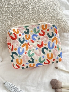 Detailed close-up of a quilted floral makeup bag with colorful abstract patterns