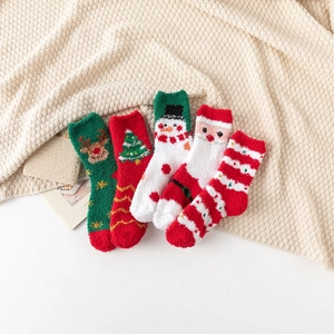 Détail de cinq paires de chaussettes de Noël en polaire corail sur une couverture en maille