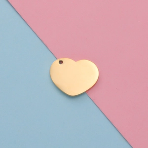 Close-up of heart-shaped gold-plated stainless steel pendant on pink and blue background