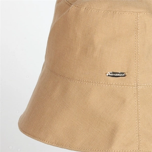 Detailed close-up of khaki sun hat with chevron weave texture and metal branding plate