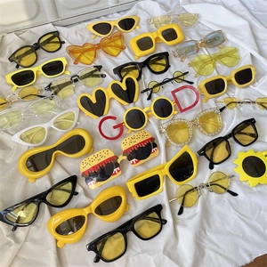 Flat lay display of trendy oversized sunglasses in various colors on white fabric background