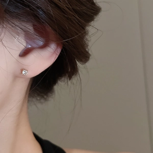 Close-up of minimalist zircon stud earring with brilliant cut stone on ear