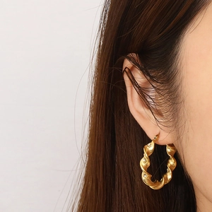 Twisted gold hoop earrings with zircon crystals on a model for a vintage aesthetic