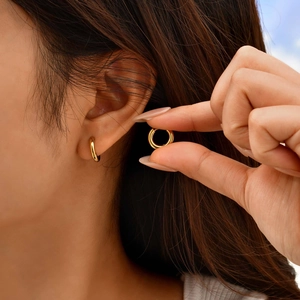 Polished gold stainless steel hoop earring shown on ear for size and style
