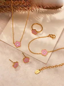 Detail van roze emaille bloemen sieradenset met ketting, ring en oorbellen op tafel