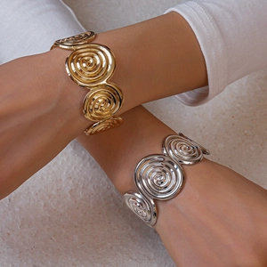 Artistic spiral geometric cuff bracelet in gold and silver finish shown on model's arms