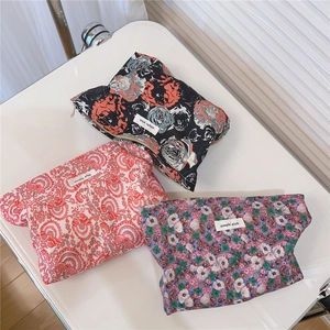 Detailed view of three vintage floral cotton makeup bags with zippers and woven labels