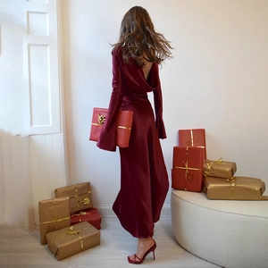 Detail of burgundy velvet backless dress with long sleeves and festive gift box background