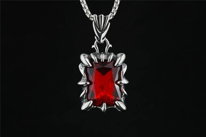 Macro shot of red rectangular gemstone held by silver dragon claw setting necklace