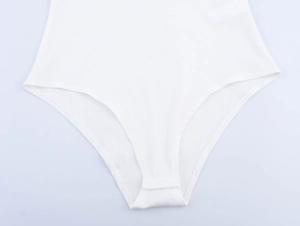 Detail view of the ribbed fabric and button crotch closure on a white slim bodysuit